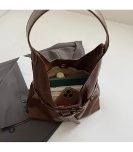 Top view of spacious brown leather tote interior showing daily items and metal clasp