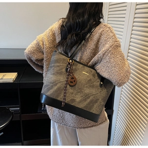 Detail of grey marble texture tote bag with black leather straps on a model's shoulder