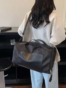 Black large capacity canvas travel bag with leather accents shown on a male model