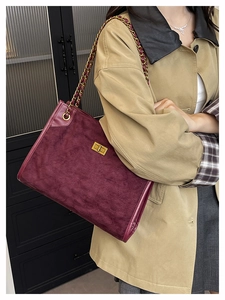 Detail of burgundy quilted suede tote bag with gold chain strap and metal clasp on model