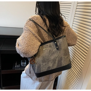 Detail of grey marble-textured tote bag with black leather straps and pretzel charm