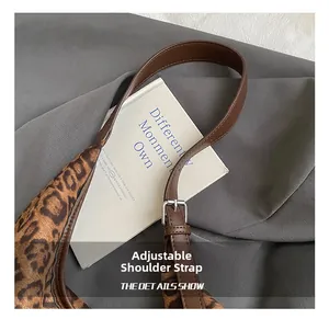 Detail of adjustable brown leather shoulder strap with silver buckle on leopard print bag