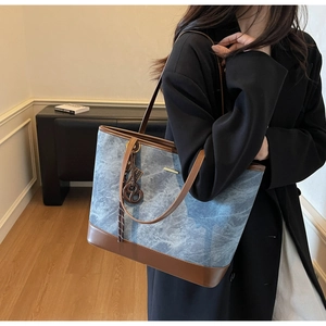 Detail of blue denim tote bag with brown leather trim and retro charm for daily commute