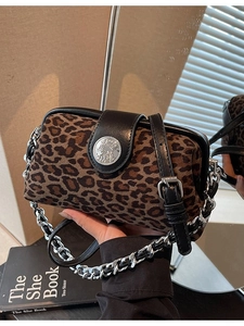 Leopard print crossbody bag with black leather trim and silver chain strap shown with props