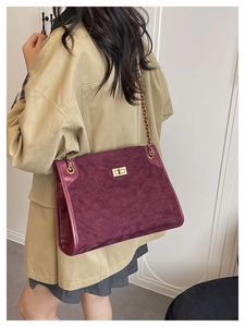 Détail du sac en daim matelassé bordeaux avec bandoulière chaîne dorée et fermoir rotatif