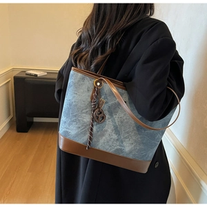 Detail of canvas and leather patchwork tote bag with decorative knot pendant