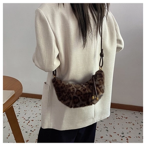 Détail du sac croissant en fausse fourrure léopard avec bandoulière en cuir noué marron
