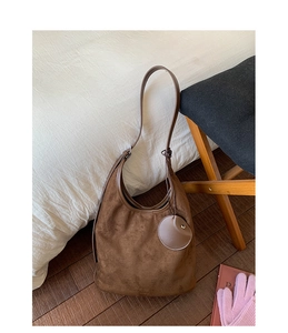 Detail shot of the deep brown faux suede hobo bag texture and round decorative pendant