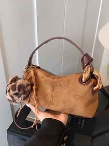 Brown suede pillow bag with thick gold chain and leopard print charm, handheld view