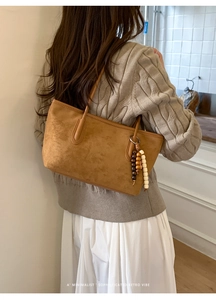Close-up of retro brown tote bag with decorative wooden beads and tassel detail