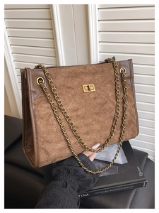Détail du sac cabas en daim marron avec matelassage en losanges et chaîne dorée sur livres