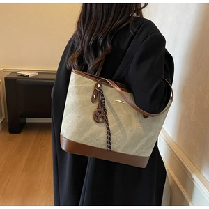 Detailed back view of a minimalist canvas and brown leather tote bag with stylish charm