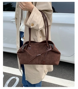 Scatto outdoor di una borsa tote in pelle scamosciata marrone scuro con pieghe naturali