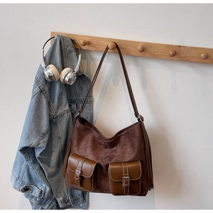 Dettaglio della borsa tote in pelle scamosciata con tasche e fibbie su gruccia in legno
