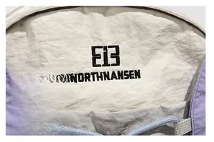 Close-up of NORTHNANSEN embroidery logo on lightweight white and purple nylon fabric