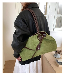 Dettaglio borsa tote in pelle scamosciata verde con cinturini marroni e fibbia in metallo