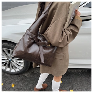Detail of vintage dark brown tote bag with metallic buckle during an outdoor shoot