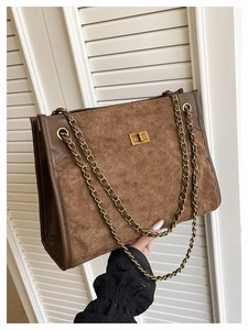 Detailed macro view of brown suede quilted tote with gold chain strap and square lock