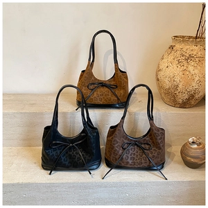 Three leopard print suede tote bags with bow details displayed on stone steps decor