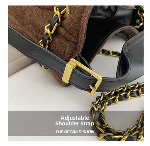 Detail of adjustable black leather strap and vintage brass hardware on a brown suede bag
