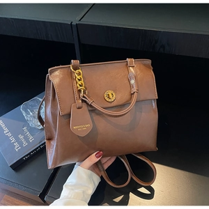 Detailed view of vintage brown leather backpack with gold chain and circular metal lock