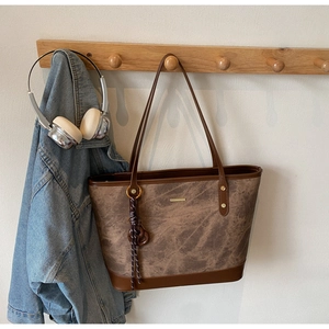 Detailed shot of brown marble texture tote bag with golden metal plaque and woven charm