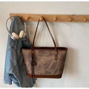 Detailed view of vintage dark brown tote bag hanging with stylish texture and gold accents