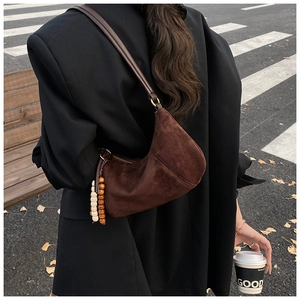 Dettaglio borsa hobo in velluto a coste marrone scuro con decorazione di perle in legno