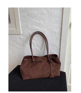 Dettaglio della borsa tote in pelle scamosciata marrone scuro con nodi a coulisse e texture