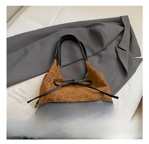 Close-up of retro leopard print suede stitching and black leather bow on a tote bag