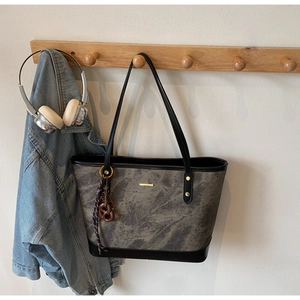 Detail of grey marble pattern tote bag with gold metal logo and resin pendant accessory
