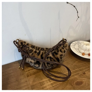 Détail du sac croissant en peluche léopard avec bandoulière à nœud et finitions dorées