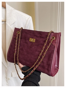 Detail of burgundy quilted suede tote with gold chain strap and turn-lock closure