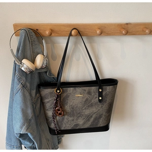 Detail of grey marble pattern tote bag with leather straps and gold metal hardware
