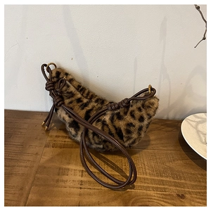 Détail du sac en peluche léopard avec fine bandoulière marron et nœuds sur bois