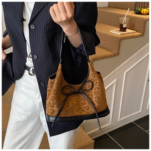Chic leopard print bucket bag with black leather bow and handle held by model