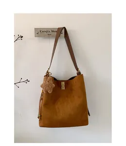 Detail of caramel frosted tote bag with gold metal clasp and brown teddy bear charm