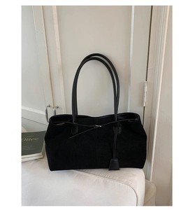 Dettaglio della borsa tote in pelle nera opaca con cuciture verticali e spalline sottili