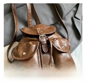 Close-up of vintage brown backpack showing white contrast stitching and silver hardware