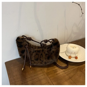 Détail du sac croissant en peluche léopard avec poignée en cuir nouée et métal doré