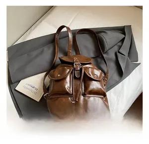 Detail of vintage brown leather backpack featuring dual front pockets and drawstring closure