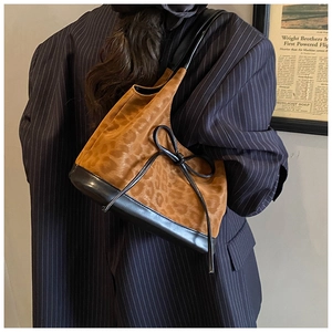 Close-up of leopard print bucket bag with black leather bow and stylish strap detail