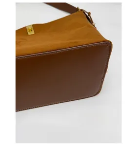 Close-up of brown suede bucket bag with reinforced leather base and gold lock detail