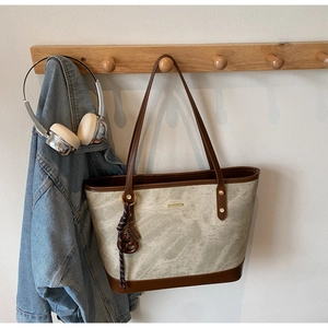 Detail of grey marble pattern tote bag with brown leather handles on wooden rack