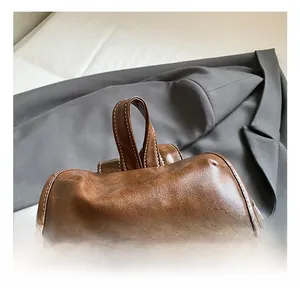 Close-up of vintage brown leather backpack handle with durable contrast stitching