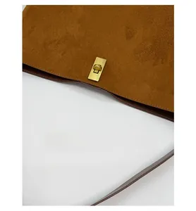 Close-up of vintage gold buckle and soft brown suede texture on a minimalist bucket bag