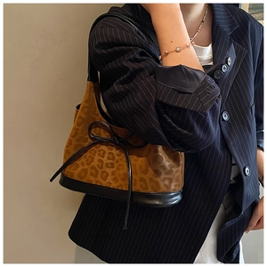 Close-up of leopard print shoulder bag with black leather base and decorative bow detail