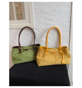 Dettaglio delle borse tote in camoscio verde e giallo con texture morbida e nappe decorative