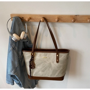 Detail of minimalist marble pattern tote bag with brown leather handles on wooden hanger