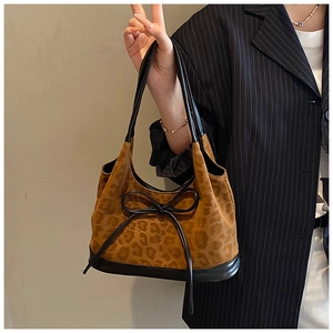 Detail of leopard print bucket bag with black leather bow accent and shoulder strap